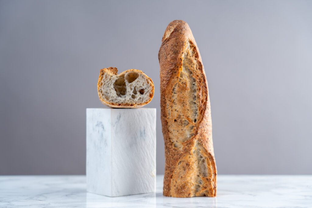 baguette tradition aux graines coupée en deux. La rencontre Boulangerie - pâtisserie